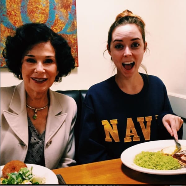 Two women smiling at Misto Caffe & Bakery, one with a plate of green rice and eggs.
