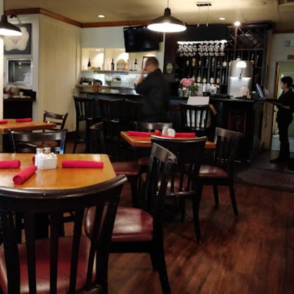Interior of Misto Caffe & Bakery with dining tables, a bar, and a server.