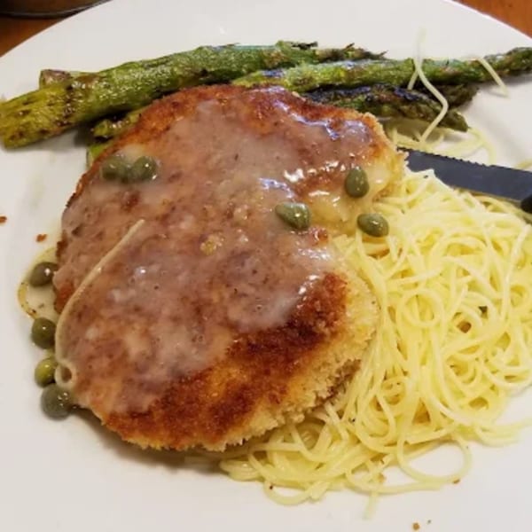 Chicken piccata with capers and sauce, served with spaghetti and grilled asparagus.