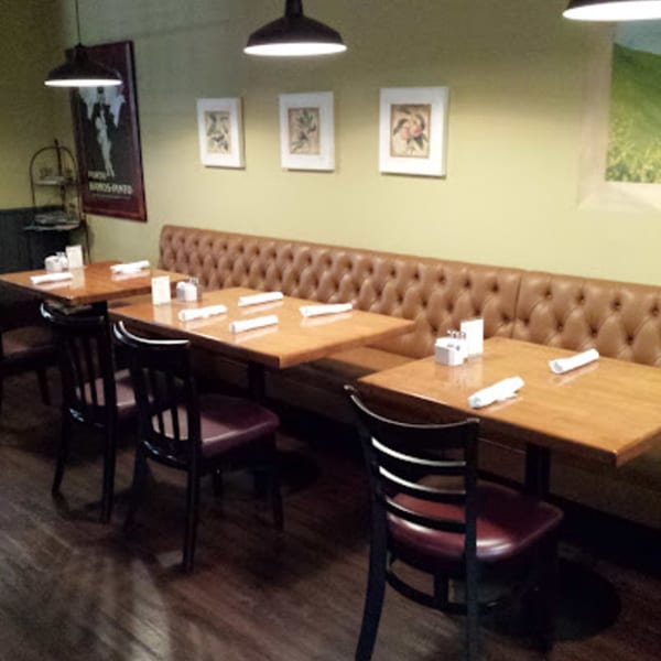 Misto Caffe & Bakery's dining area with wooden tables, dark chairs, and a long brown booth.