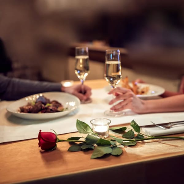 Couple enjoying a romantic dinner with champagne, a red rose, and candlelight at Misto Caffe & Bakery.