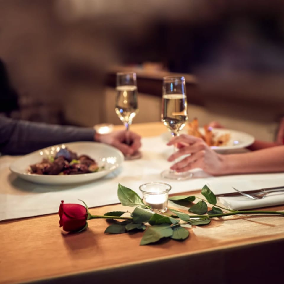 Couple enjoying a romantic dinner with champagne, a red rose, and candlelight at Misto Caffe & Bakery.