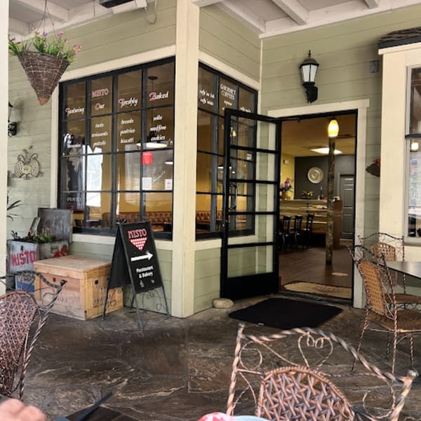 Exterior of Misto Caffe & Bakery with outdoor seating and an open door revealing the interior.