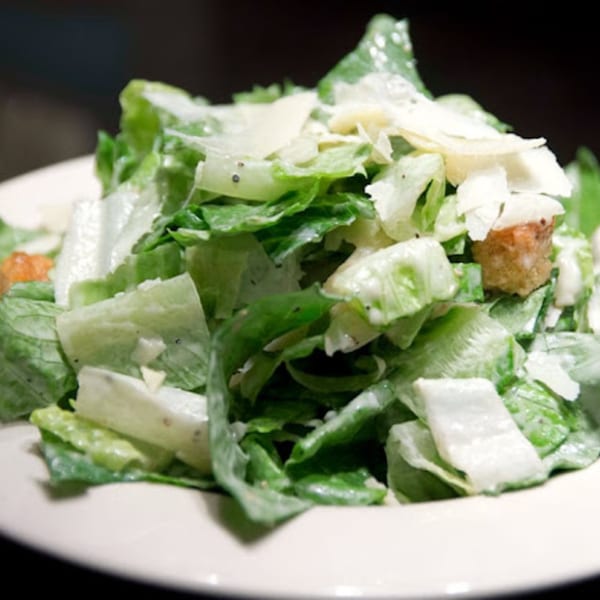 Close-up of a Caesar salad with crisp romaine lettuce, croutons, and shaved Parmesan cheese.